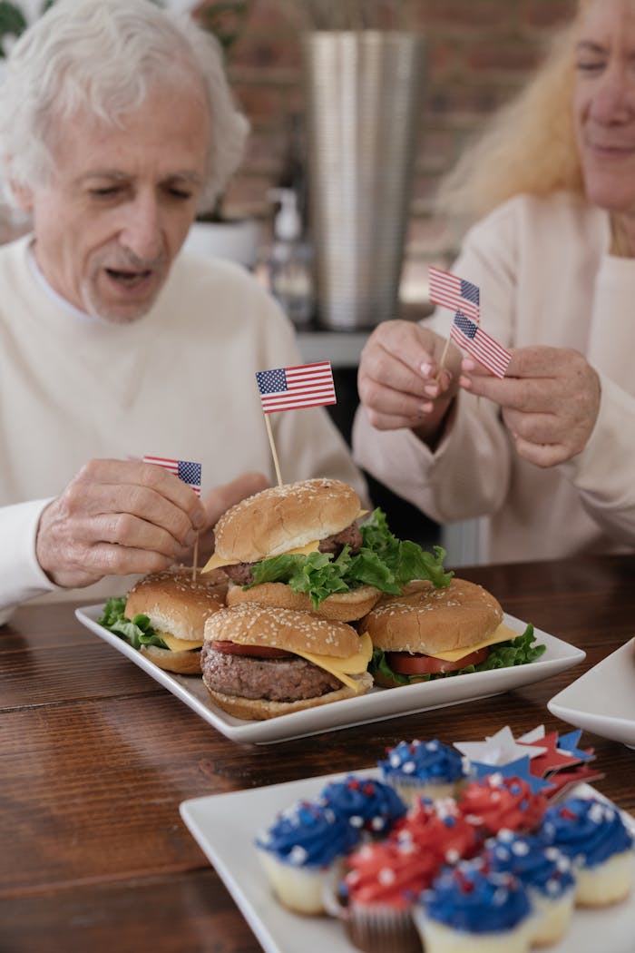 Senior adults enjoying American themed burgers with flags, perfect for a patriotic celebration.